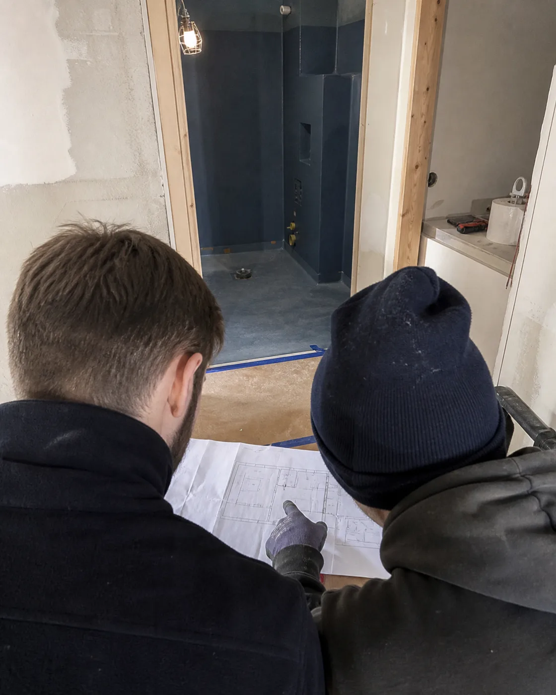 Två hantverkare planerar arbetet tillsammans utifrån en ritning